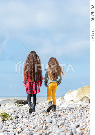 Back view of two little girls in red tartan dress, green jumper and yellow leggings walking at Hope Gap beach near Cuckmere Haven located between Seaford and Eastbourne in East Sussex, UK Back view of two little girls in red tartan dress, green jumper and yellow leggings walking at Hope Gap beach near Cuckmere Haven located between Seaford and Eastbourne in East Sussex, UK 95679052