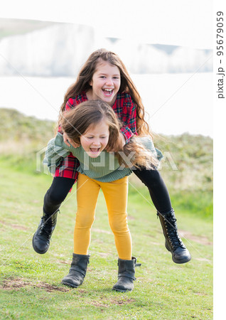 Two little girls sisters playing outdoor near Cuckmere beach located between Eastbourne and Seaford, East Sussex, British south coast, selective focus 95679059
