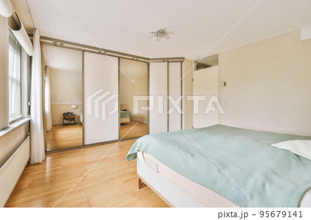 Comfortable bed placed near green wall in modern minimalist style mansard bedroom with windows 95679141