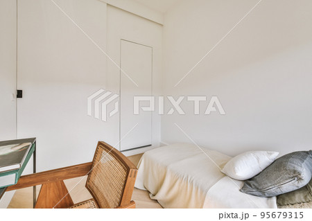 Home interior design of bedroom with bed and wooden wardrobe placed in corner near window in modern apartment 95679315