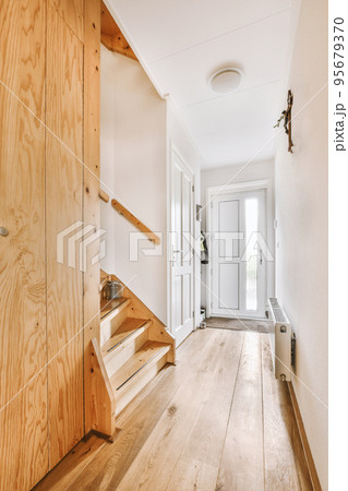 White hallway with wooden stairway leading to second floor of modern luxury apartment with minimalist interior design White hallway with wooden stairway leading to second floor of modern luxury apartment with minimalist interior design 95679370
