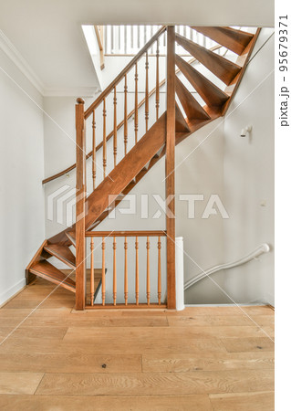White hallway with wooden stairway leading to second floor of modern luxury apartment with minimalist interior design White hallway with wooden stairway leading to second floor of modern luxury apartment with minimalist interior design 95679371