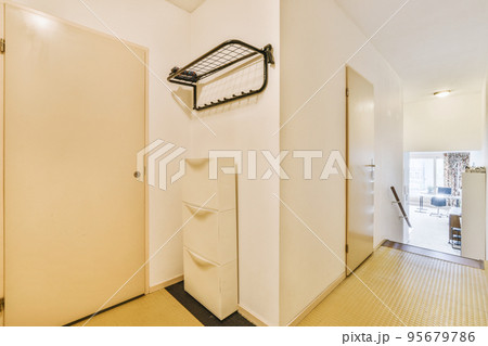 Narrow corridor with white walls and doors leading to spacious room with windows and parquet floor in modern apartment Narrow corridor with white walls and doors leading to spacious room with windows and parquet floor in modern apartment 95679786