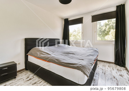 Home interior design of bedroom with bed and wooden wardrobe placed in corner near window in modern apartment Home interior design of bedroom with bed and wooden wardrobe placed in corner near window in modern apartment 95679808