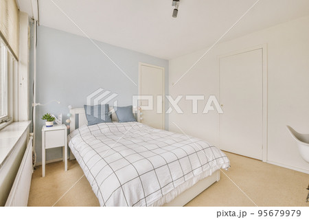 Home interior design of bedroom with bed and wooden wardrobe placed in corner near window in modern apartment 95679979