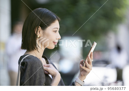 スマートフォンの画面を見る若い女性の横顔 95680377