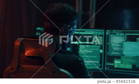 Back view of guy using futuristic headset with LED lights programs develops code Back view of guy using futuristic headset with LED lights programs develops code 95681516