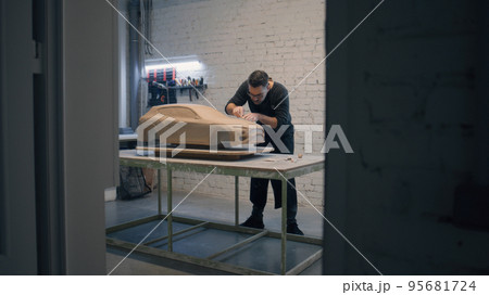 Male designer creates prototype model of a car made of clay using sculpting tool 95681724