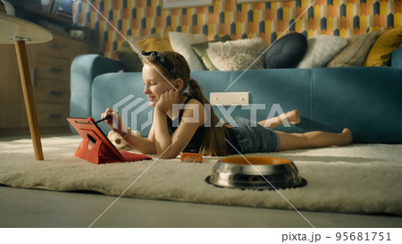 Young girl choosing video on tablet near dog Young girl choosing video on tablet near dog 95681751