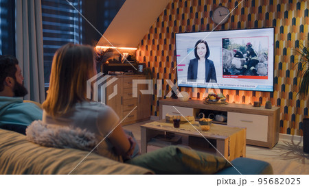 Couple watching breaking TV news about disaster Couple watching breaking TV news about disaster 95682025
