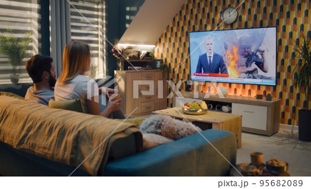 Couple watching TV news about war in Ukraine Couple watching TV news about war in Ukraine 95682089