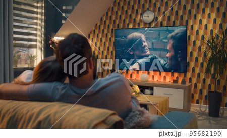Couple on sofa watching action movie Couple on sofa watching action movie 95682190