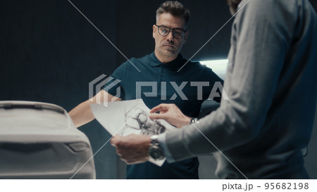 Car designers discuss design of the car infront of sculpture of a prototype car 95682198
