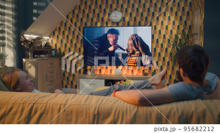 Man and woman watching action movie on TV Man and woman watching action movie on TV 95682212