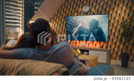 Couple on sofa watching action movie 95682235