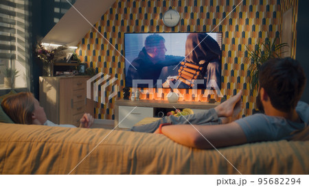 Man and woman watching action movie on TV Man and woman watching action movie on TV 95682294