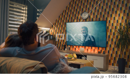 Couple on sofa watching action movie 95682308