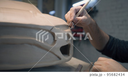 Car designer works on prototype car using loop tools to create details in design 95682434