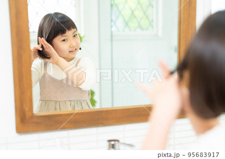 鏡を見て髪の毛をセットする小学生の女の子 鏡を見て髪の毛をセットする小学生の女の子 95683917