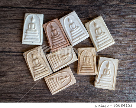 Thai buddha amulet isolated on wooden background. 95684152