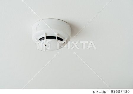 Smoke sensor detector mounted on roof in home or apartment. Safety and conflagration security concept 95687480