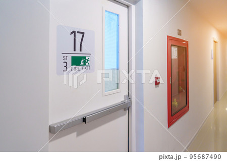 Fire extinguisher system on the wall with Fire Exit door sign for emergency. Stairwell fire for escape in building or apartment 95687490