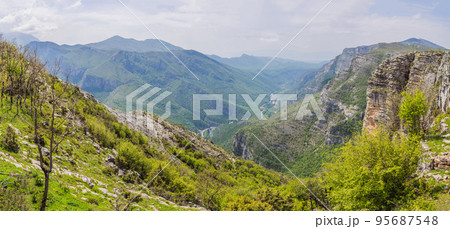 Blue river running through green valley toward distant mountains. Beautiful mountains of Montenegro and the river Cievna 95687548