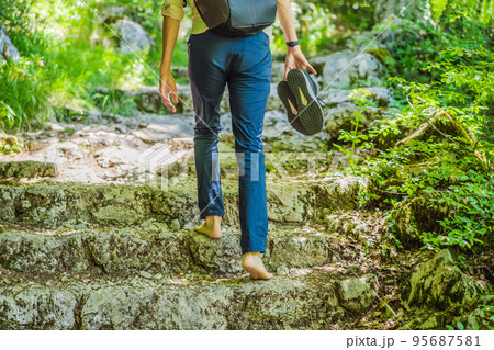 Man tourist climb barefoot the mountain to the Ostrog. It is a tradition to climb barefoot. Monastery of Ostrog, Serbian Orthodox Church situated against a vertical background, high up in the large Man tourist climb barefoot the mountain to the Ostrog. It is a tradition to climb barefoot. Monastery of Ostrog, Serbian Orthodox Church situated against a vertical background, high up in the large 95687581
