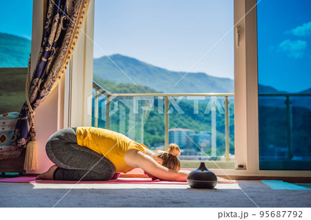 Mindful healthy woman practicing yoga at home. Sitting on the floor doing yoga for mental balance relaxing on stress. Enjoying time uses an aroma diffuser 95687792