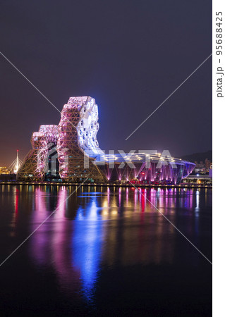 Night view of Kaohsiung Music Center with a view from Love River. The white hexagonal building structure on the riverbank in Kaohsiung, Taiwan. Night view of Kaohsiung Music Center with a view from Love River. The white hexagonal building structure on the riverbank in Kaohsiung, Taiwan. 95688425