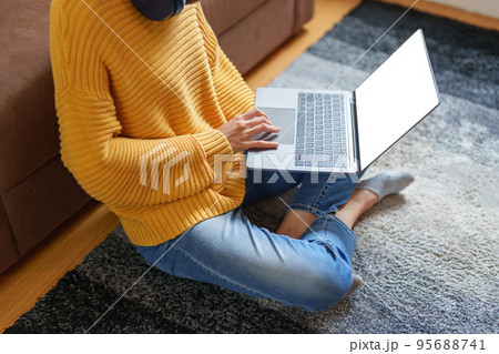 Portrait of a young Asian woman using a computer on the sofa. 95688741