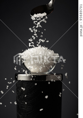 Sea salt is poured into a small bowl. 95689701