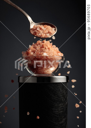 Pink salt is poured into a small bowl. Pink salt is poured into a small bowl. 95689703