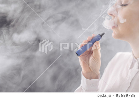 Caucasian woman smokes a disposable vape in the studio. Caucasian woman smokes a disposable vape in the studio. 95689738