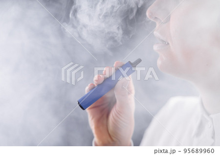 Caucasian woman smokes a disposable vape in the studio. 95689960