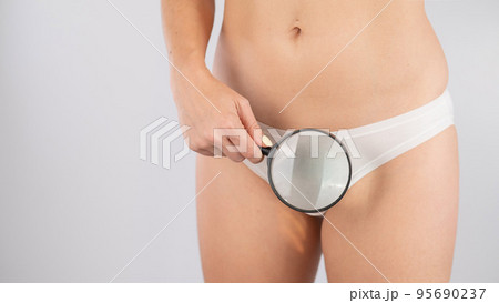 A woman in white shorts holds a magnifying glass on a white background. 95690237