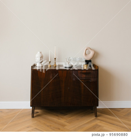 Classic wooden chest of drawers in a minimalist style with a decor of candles, vases in the living room Classic wooden chest of drawers in a minimalist style with a decor of candles, vases in the living room 95690880