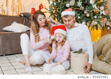 Christmas family. Happy portrait dad, mom and daughter in santa hats sitting 95692001