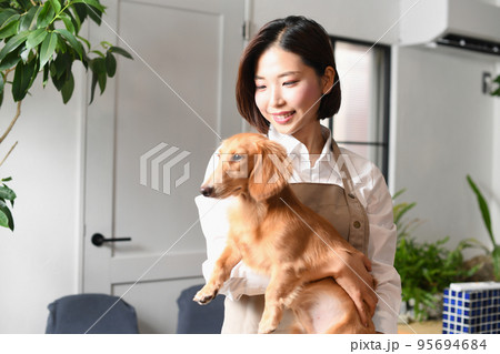 犬（ペット）を抱っこするトリマーの女性 95694684