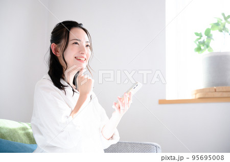 スマホを素敵な笑顔で持つかわいい女性　 95695008