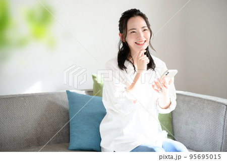 スマホをもって考えるかわいい女性　 95695015