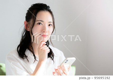 スマホをもって考えるかわいい女性 スマホをもって考えるかわいい女性 95695192