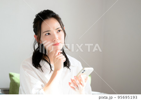 スマホをもって考えるかわいい女性 スマホをもって考えるかわいい女性 95695193