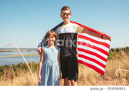 Two happy children with the flag of America in nature on a sunny day. 95696861