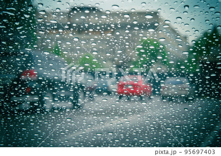 Road view through car window with rain drops. Car window on a rainy day. Highway view, background is out of focus. 95697403