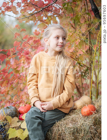 Girl in the hay with pumpkins Girl in the hay with pumpkins 95697603