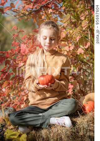 Girl in the hay with pumpkins Girl in the hay with pumpkins 95697604