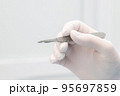 scalpel in the surgeon's hand close-up. a sterile glove on the hand. start of operation 95697859