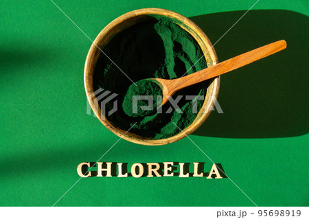 Blue-green algae with message CHLORELLA and spirulina powder in bamboo eco bowl. Super powder in spoon. Detox superfood. Natural supplement of algae Blue-green algae with message CHLORELLA and spirulina powder in bamboo eco bowl. Super powder in spoon. Detox superfood. Natural supplement of algae 95698919