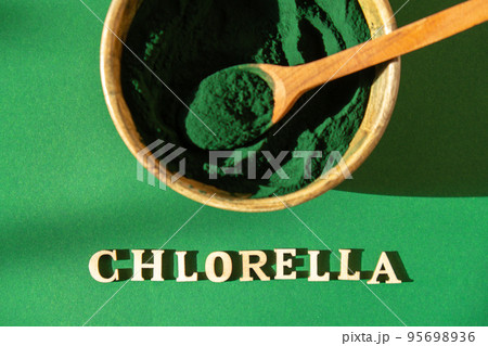 Blue-green algae with message CHLORELLA and spirulina powder in bamboo eco bowl. Super powder in spoon. Detox superfood. Natural supplement of algae Blue-green algae with message CHLORELLA and spirulina powder in bamboo eco bowl. Super powder in spoon. Detox superfood. Natural supplement of algae 95698936
